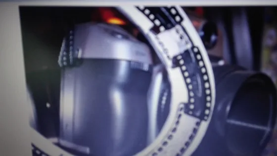 Obrócone ujęcie jasnej podkowy z czarnym motywem taśmy filmowej, przy metalowych naczyniach.