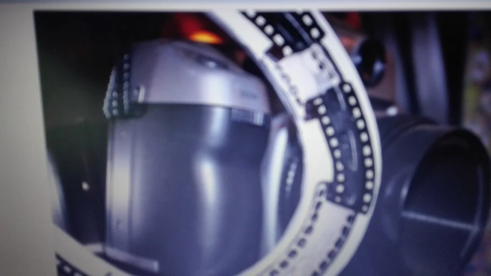 Obrócone ujęcie jasnej podkowy z czarnym motywem taśmy filmowej, przy metalowych naczyniach.